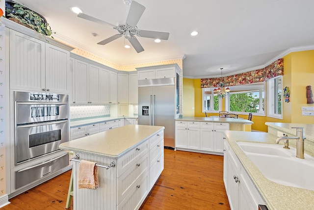 kitchen featuring sink, hanging light fixtures, light hardwood / wood-style flooring, and appliances with stainless steel finishes