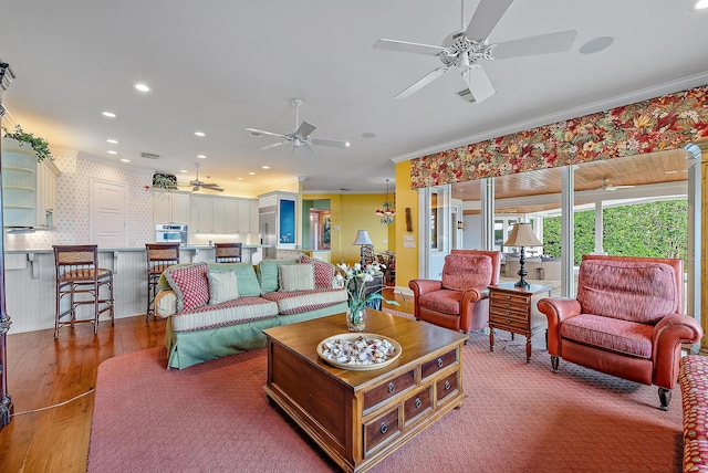 living room with crown molding, wood-type flooring, and ceiling fan