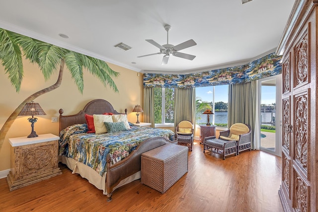 bedroom with ceiling fan, a water view, hardwood / wood-style floors, access to exterior, and ornamental molding