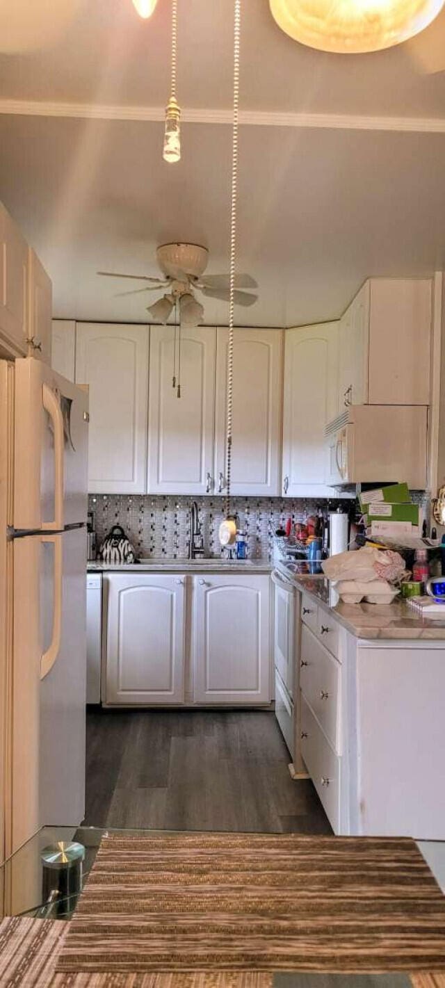 kitchen featuring stove, dark wood-type flooring, white refrigerator, decorative backsplash, and white cabinetry