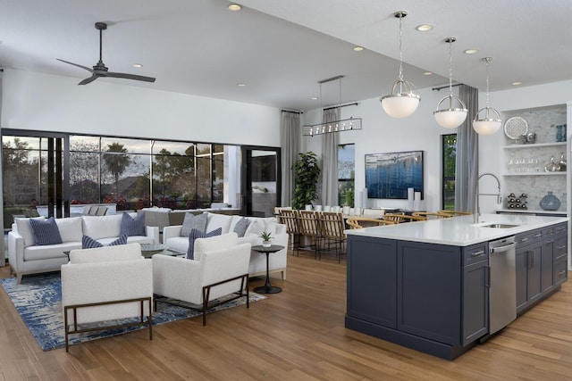 kitchen featuring gray cabinetry, a kitchen island with sink, sink, light hardwood / wood-style flooring, and decorative light fixtures