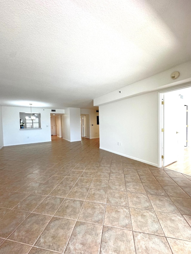 unfurnished living room with a textured ceiling and tile patterned flooring