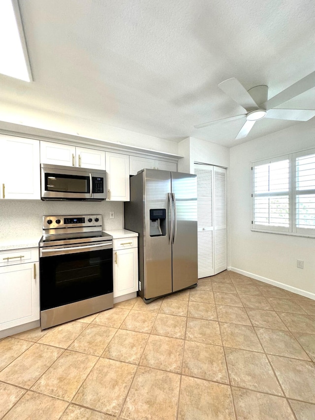 kitchen with light tile patterned flooring, white cabinetry, appliances with stainless steel finishes, and ceiling fan