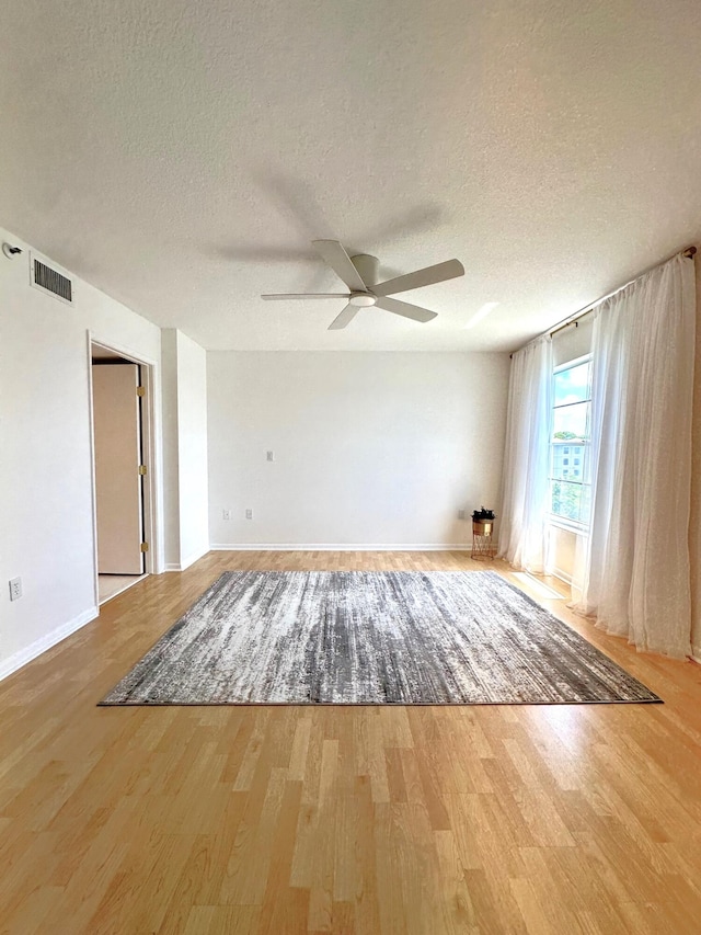 spare room with light hardwood / wood-style floors, a textured ceiling, and ceiling fan