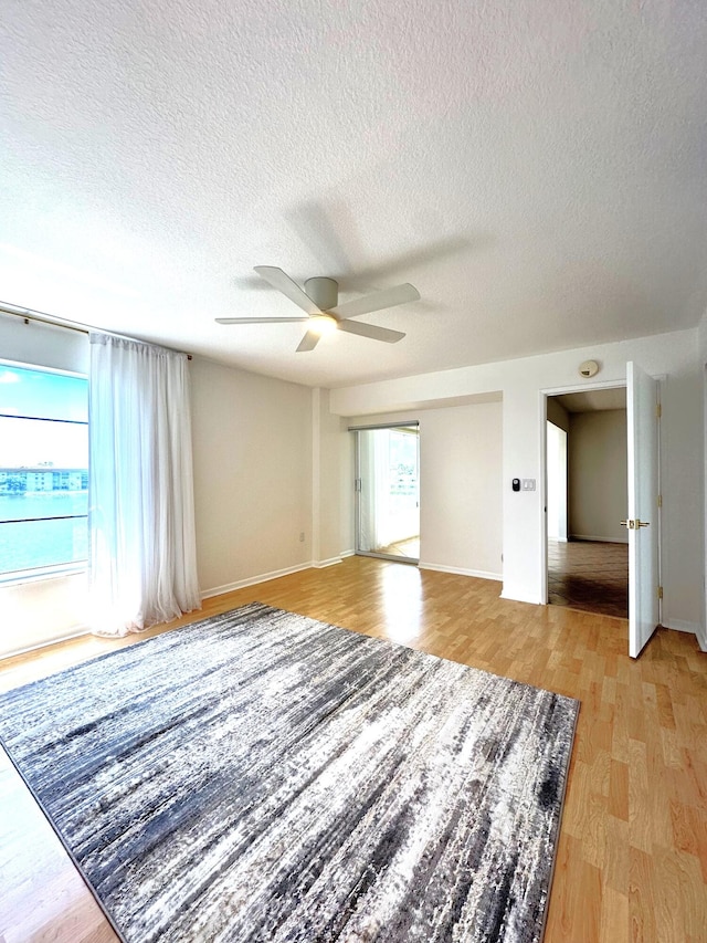 interior space with a textured ceiling, ceiling fan, and light wood-type flooring