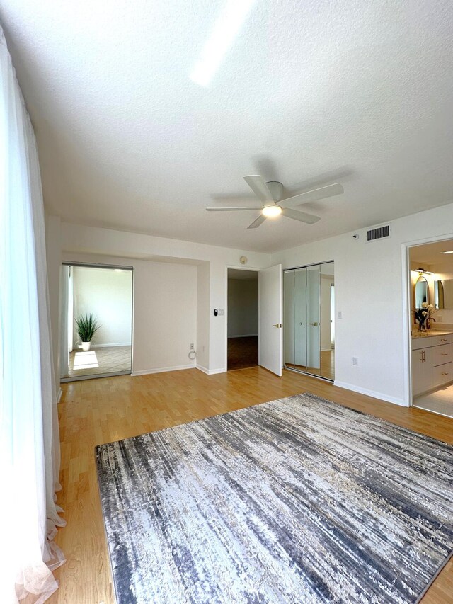 unfurnished living room featuring a textured ceiling, ceiling fan, and light wood-type flooring