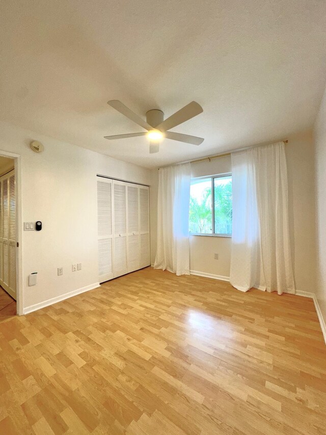 unfurnished bedroom with light hardwood / wood-style floors, a closet, and ceiling fan