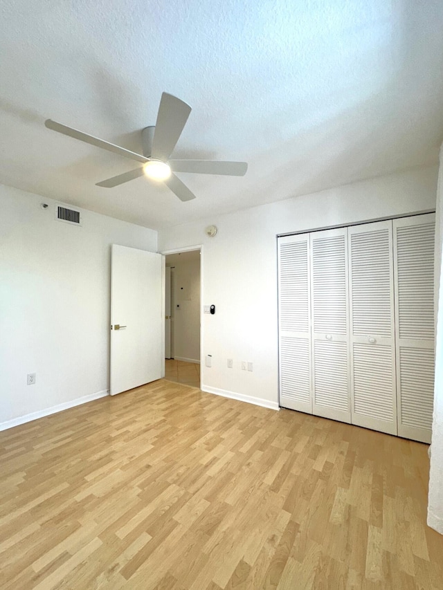 unfurnished bedroom with a textured ceiling, light wood-type flooring, ceiling fan, and a closet