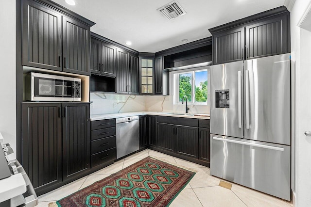 kitchen featuring light tile patterned floors, backsplash, sink, and stainless steel appliances