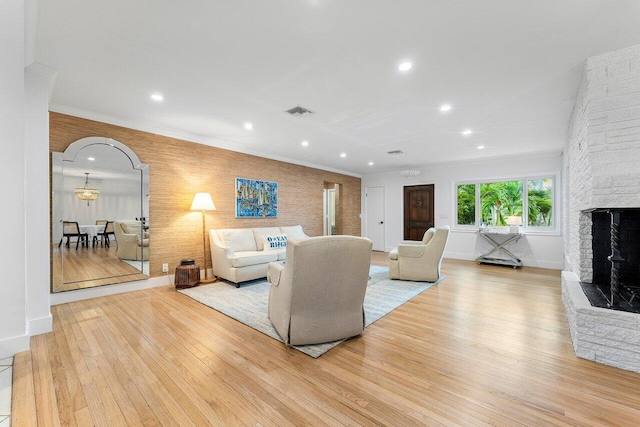 living room with light hardwood / wood-style floors, ornamental molding, and a fireplace