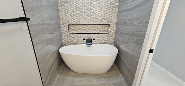 bathroom with a tub to relax in and tile walls