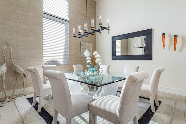 dining space featuring light hardwood / wood-style flooring, a towering ceiling, and an inviting chandelier