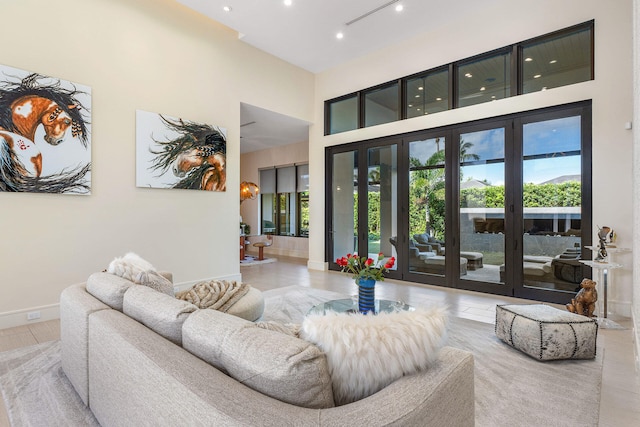 living room with french doors, light tile patterned floors, and a high ceiling