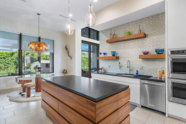 kitchen featuring backsplash, stainless steel appliances, sink, an inviting chandelier, and white cabinetry