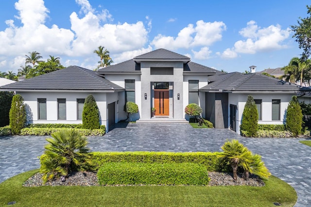 view of front of property featuring a tile roof, decorative driveway, and stucco siding