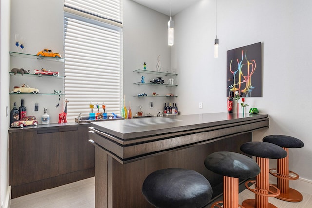 bar with dark brown cabinets and decorative light fixtures