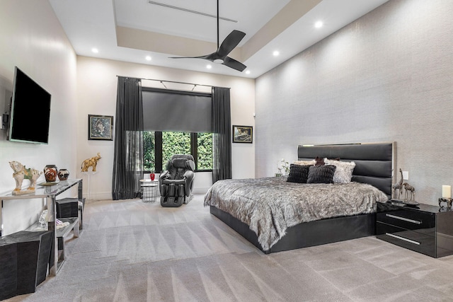 bedroom featuring a high ceiling, light colored carpet, and ceiling fan