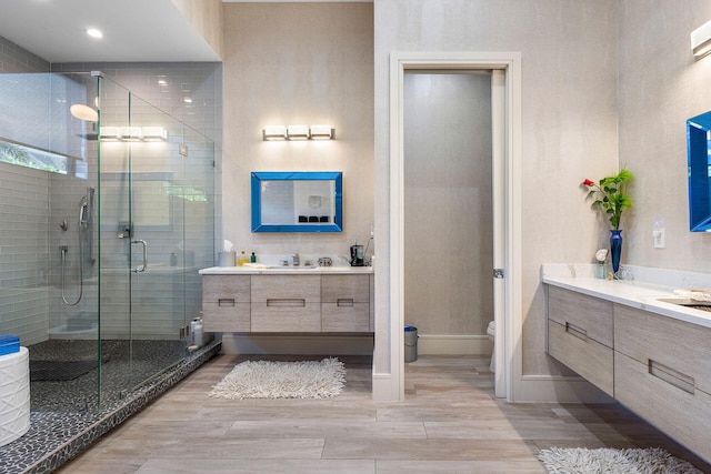 bathroom featuring vanity, toilet, a shower with shower door, and wood-type flooring