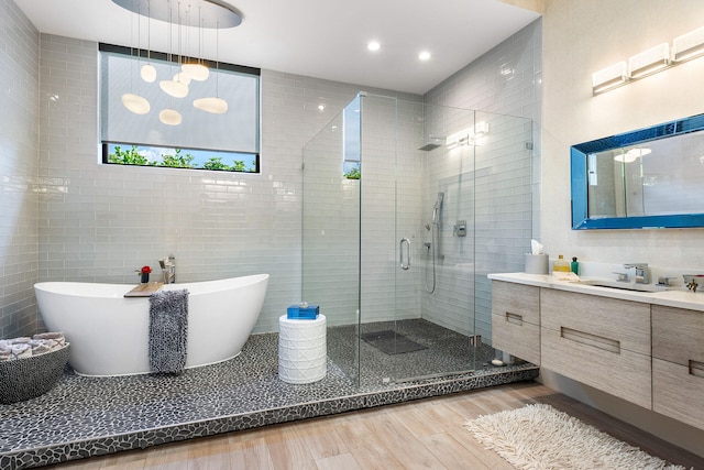 bathroom with hardwood / wood-style floors, vanity, tile walls, and independent shower and bath