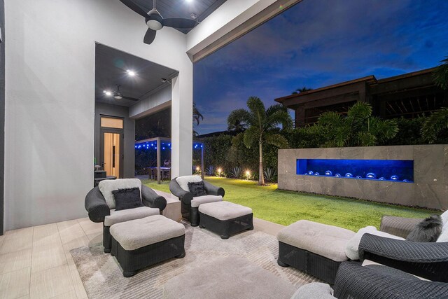 back house at dusk with a lawn, a patio area, and ceiling fan