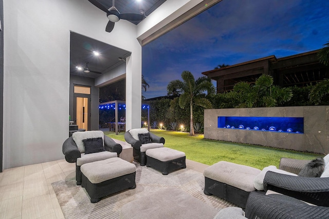 patio terrace at dusk with ceiling fan and a yard