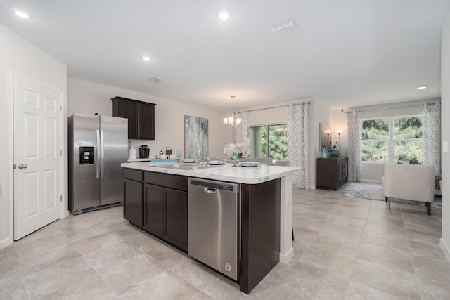 kitchen with sink, a notable chandelier, decorative light fixtures, a kitchen island with sink, and appliances with stainless steel finishes