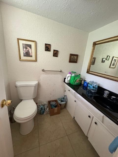 bathroom featuring tile flooring, toilet, oversized vanity, and a textured ceiling