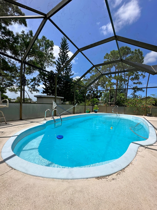 view of swimming pool featuring a lanai and a patio area