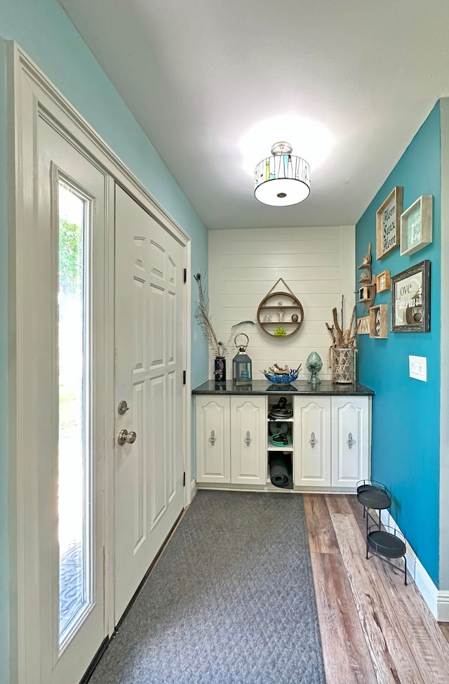 kitchen with a kitchen breakfast bar, hanging light fixtures, a kitchen island, backsplash, and wood-type flooring