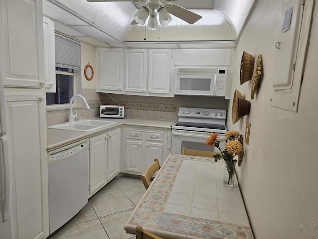 kitchen featuring white appliances, white cabinets, sink, light tile patterned floors, and tasteful backsplash