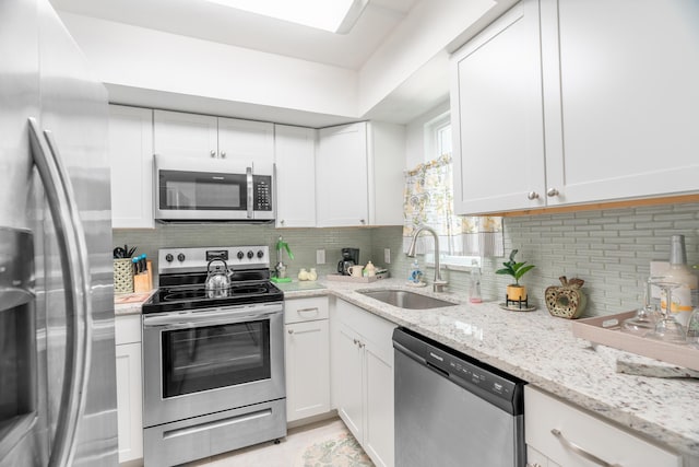 kitchen with a sink, stainless steel appliances, tasteful backsplash, and white cabinetry