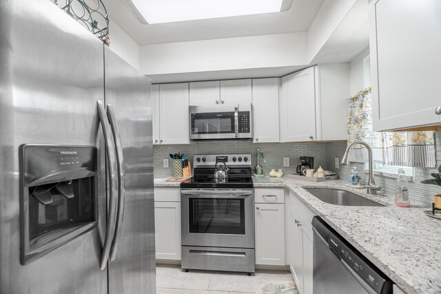 kitchen featuring decorative backsplash, white cabinets, appliances with stainless steel finishes, and a sink