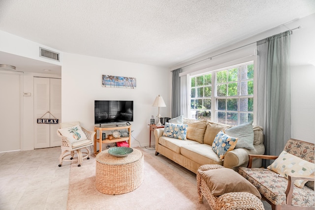 living area with light tile patterned floors, visible vents, and a textured ceiling