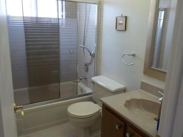 full bathroom featuring vanity, combined bath / shower with glass door, tile patterned floors, and toilet