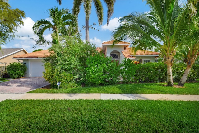 mediterranean / spanish home with a garage and a front lawn