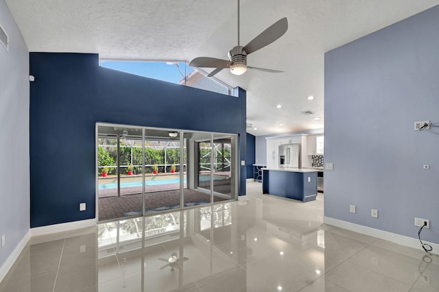 empty room featuring high vaulted ceiling, a textured ceiling, ceiling fan, and light tile patterned floors