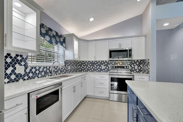 kitchen featuring tasteful backsplash, sink, appliances with stainless steel finishes, lofted ceiling, and light tile patterned floors