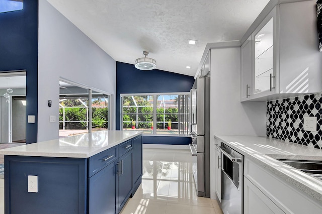 kitchen featuring dishwashing machine, decorative backsplash, stainless steel fridge, lofted ceiling, and light tile patterned floors