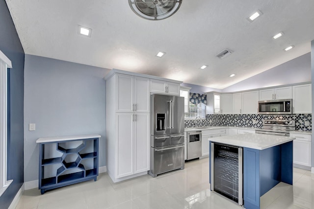 kitchen with lofted ceiling, light tile patterned flooring, stainless steel appliances, and wine cooler