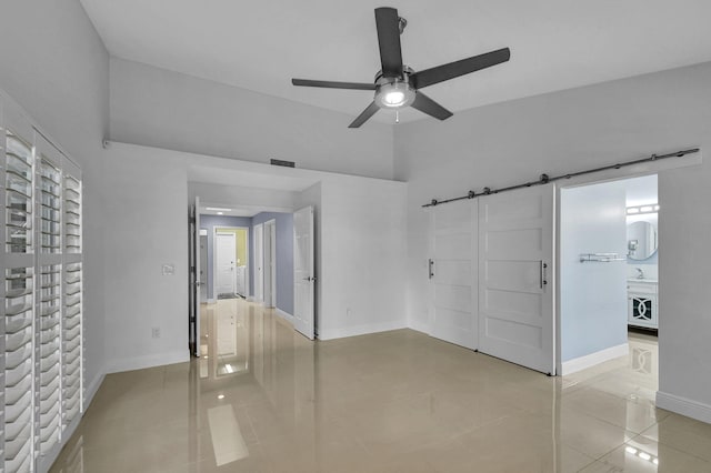 tiled spare room featuring ceiling fan and a barn door