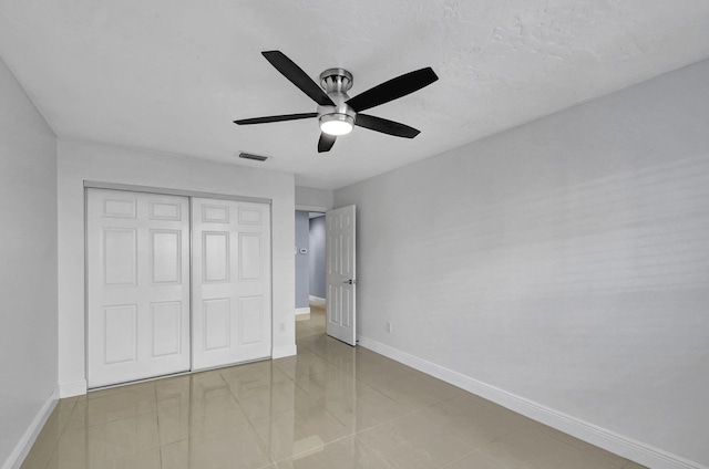 unfurnished bedroom featuring a closet, light tile patterned floors, and ceiling fan