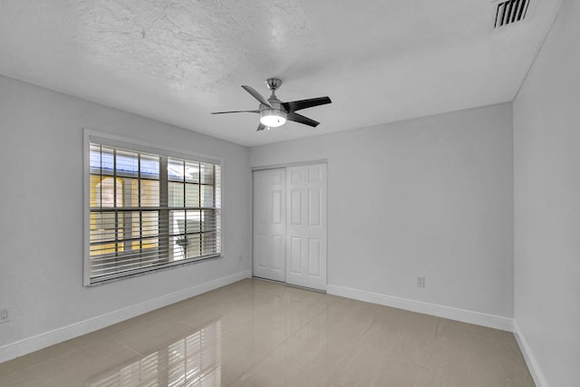 tiled empty room featuring ceiling fan