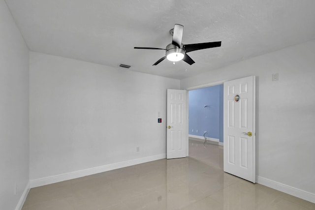 spare room featuring tile patterned floors and ceiling fan