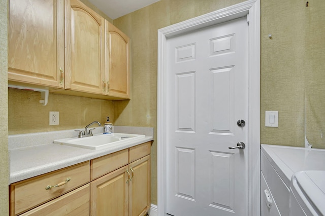 washroom with cabinets, washing machine and clothes dryer, and sink