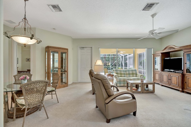 carpeted living room with ceiling fan and a textured ceiling