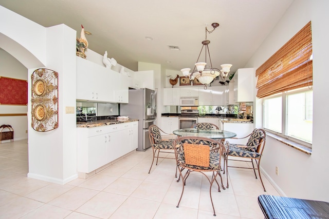 kitchen with light tile floors, decorative light fixtures, white cabinetry, and appliances with stainless steel finishes