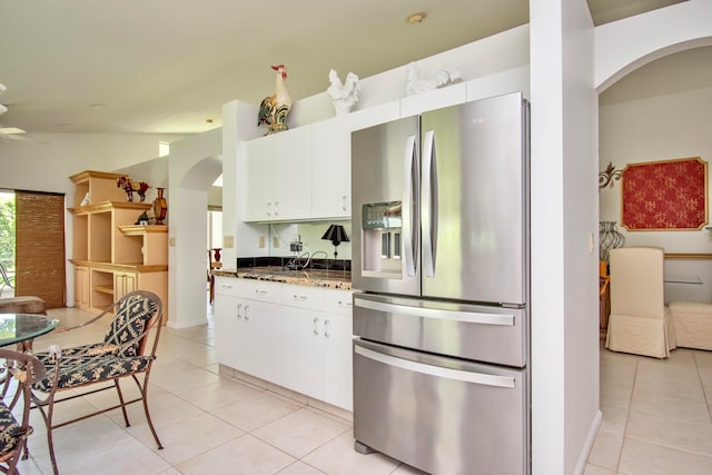 kitchen with light tile floors, white cabinets, stainless steel fridge with ice dispenser, and dark stone countertops