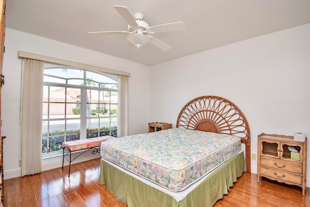 bedroom with ceiling fan, multiple windows, and hardwood / wood-style floors