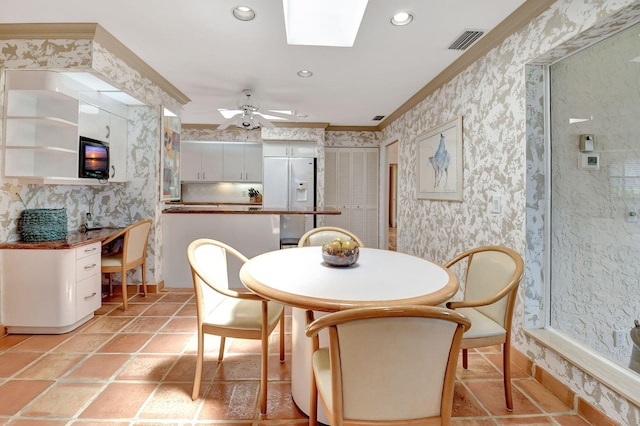 dining room with ceiling fan, ornamental molding, and a skylight