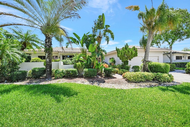 mediterranean / spanish house featuring a garage and a front lawn